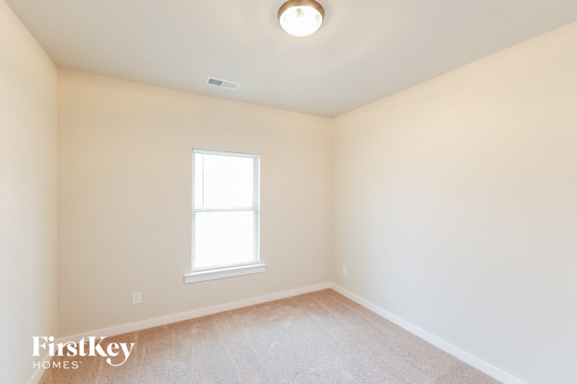 A room with a window and a carpeted floor.
