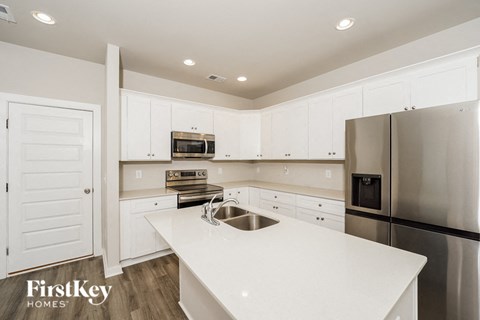 a white kitchen with stainless steel appliances and white counter tops
