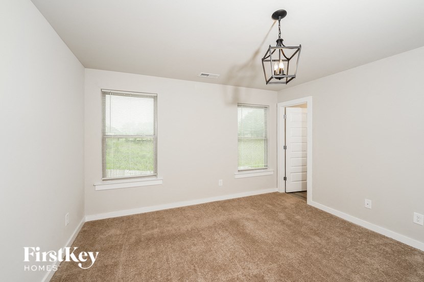 an empty living room with a lamp and two windows