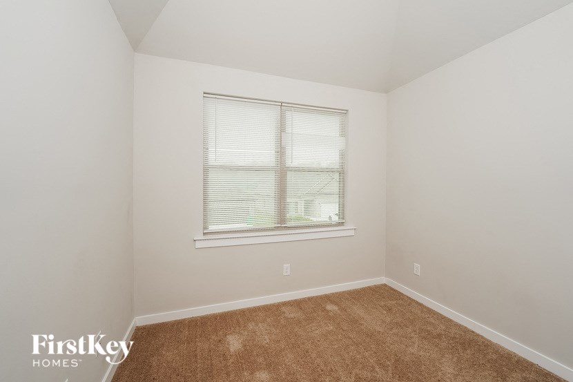 a bedroom with a window and a carpet