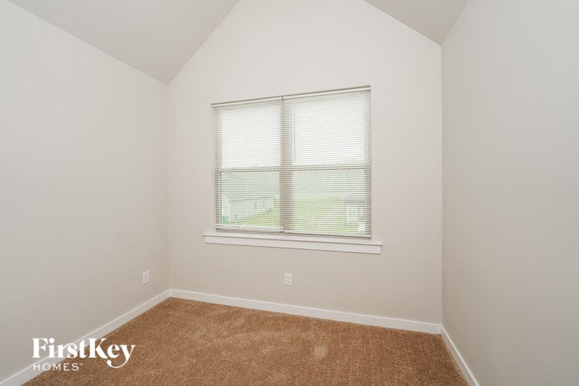the bedroom of a home with a window and carpet