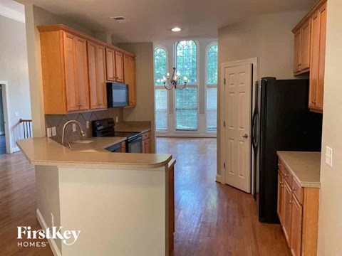 A kitchen with wooden cabinets and a black refrigerator.