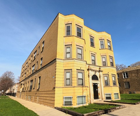 A yellow building with a black door and windows.