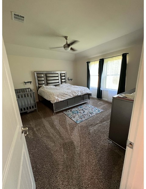 a bedroom with a crib and a bed and a ceiling fan