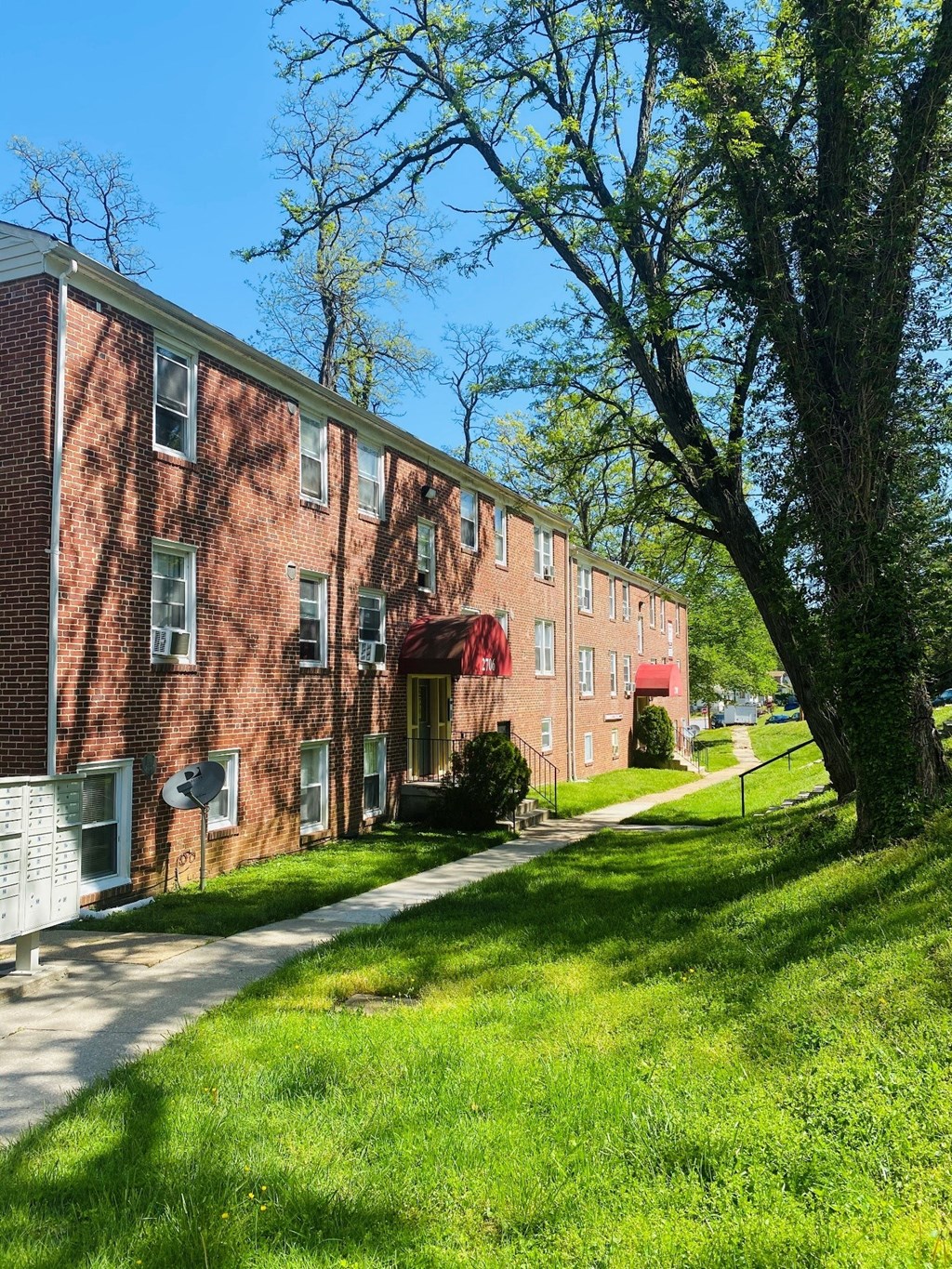 a red brick apartment building with green grass and trees