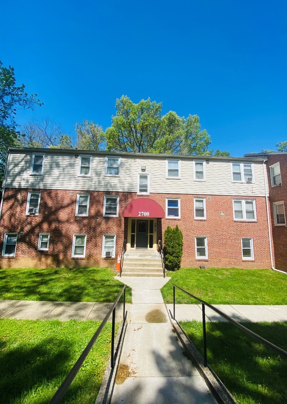 front view of a brick building with stairs and grass