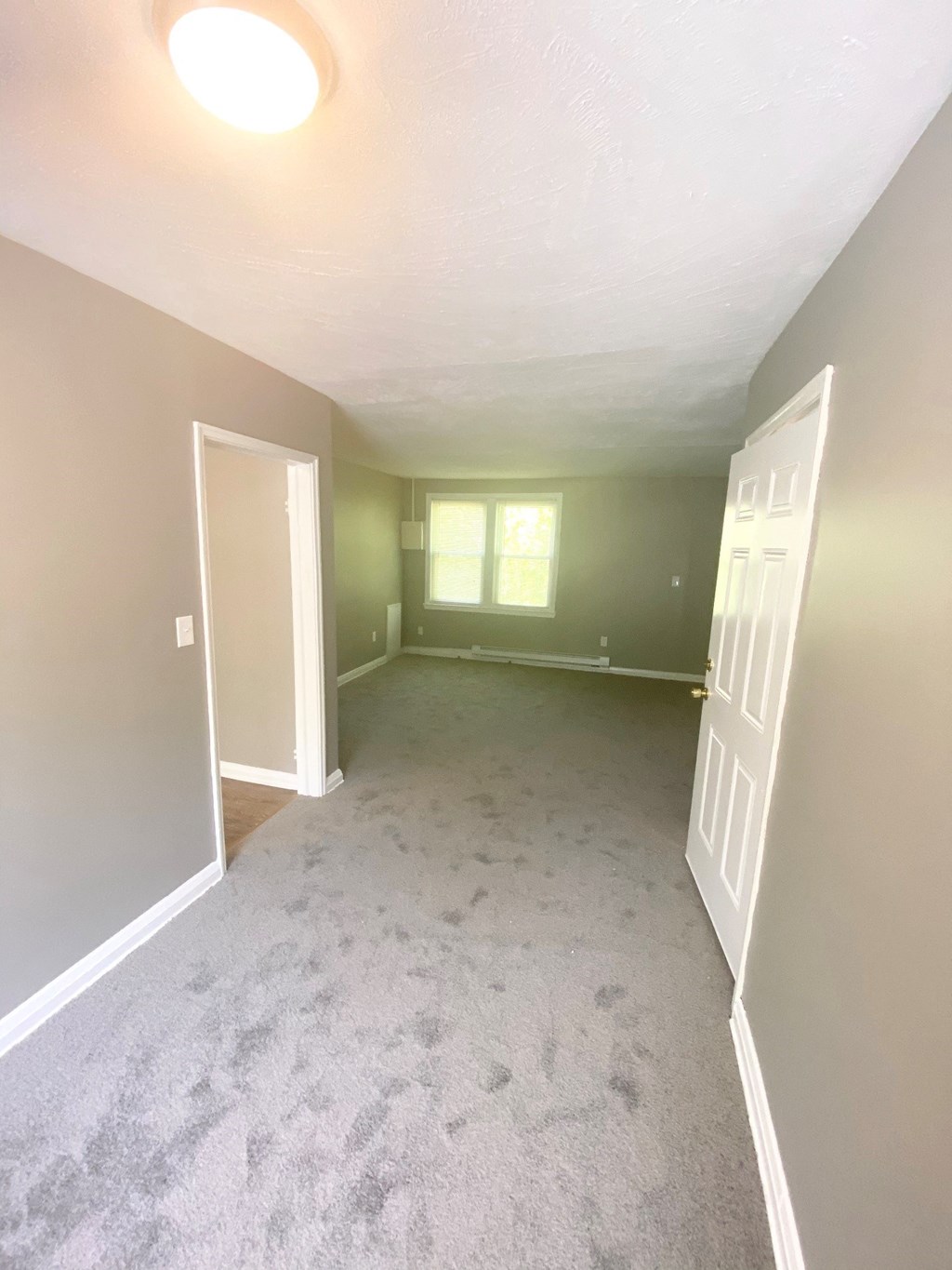 an empty room with a carpeted floor and a window
