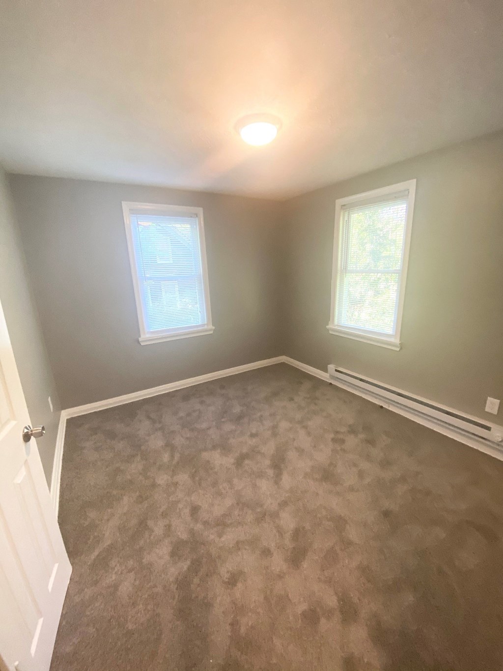 a empty room with carpet and two windows