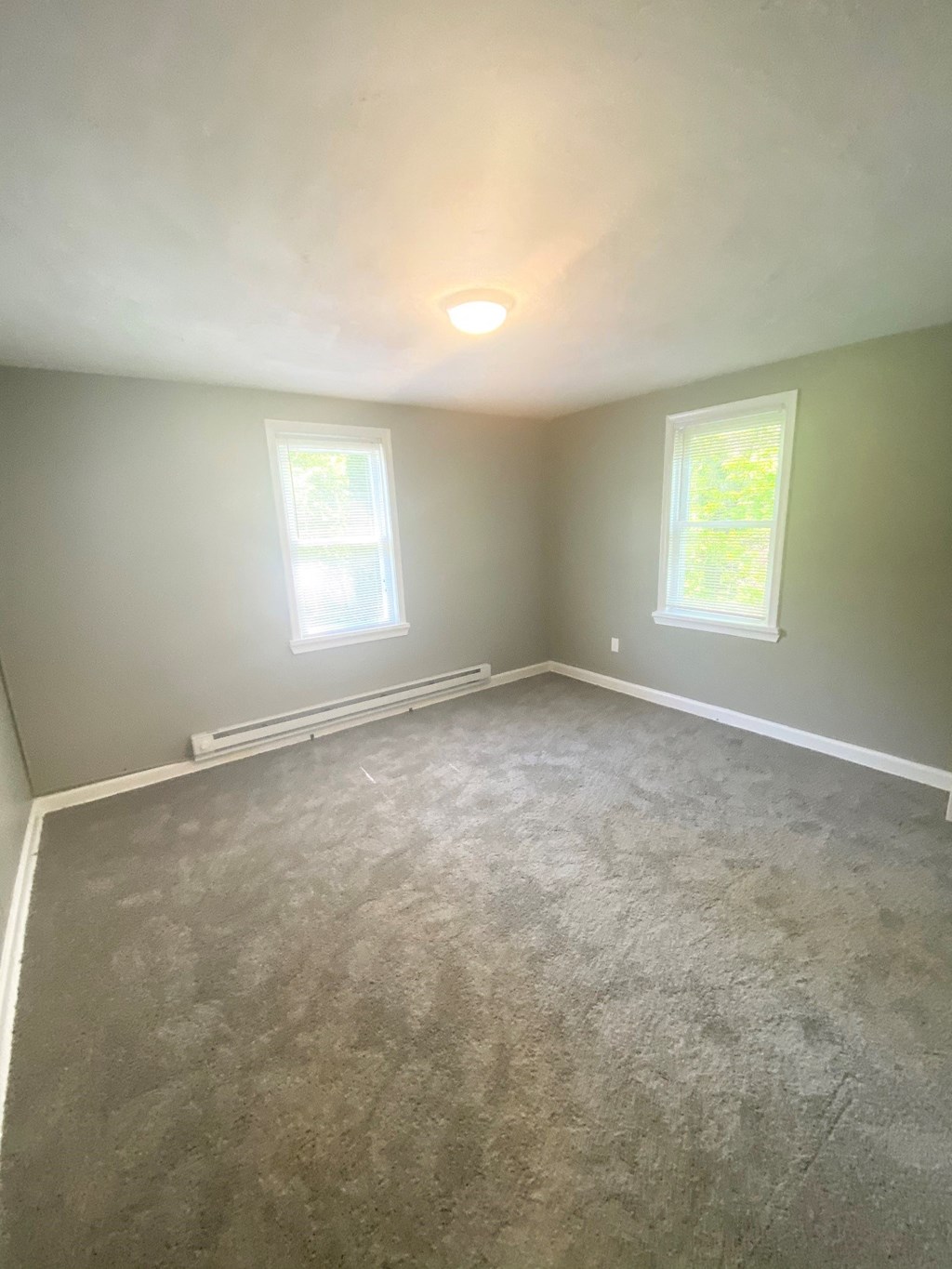 a empty living room with carpet and two windows