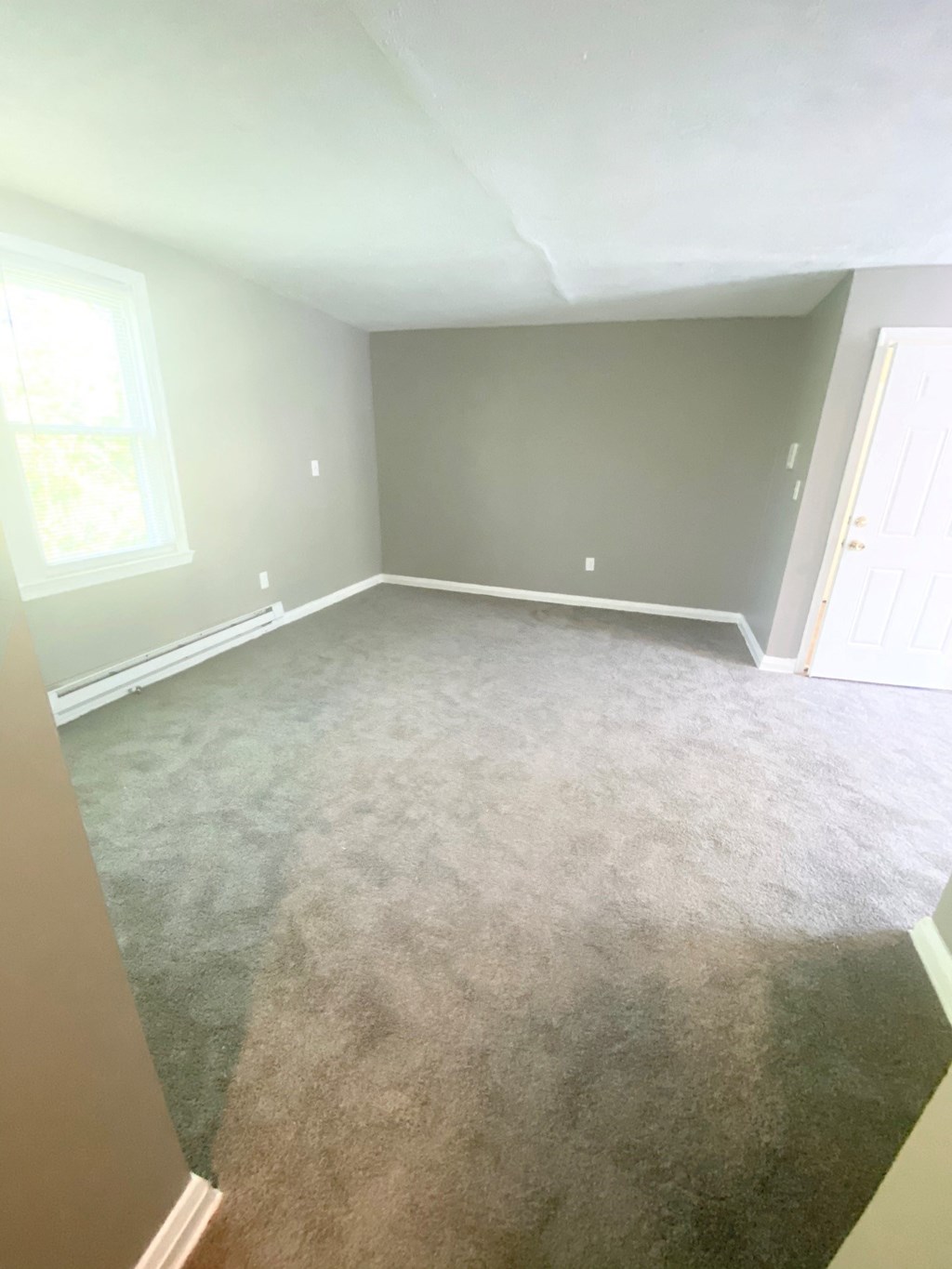 an empty room with a carpeted floor and grey walls