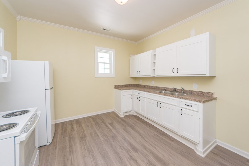a kitchen with white cabinets and a sink and a refrigerator