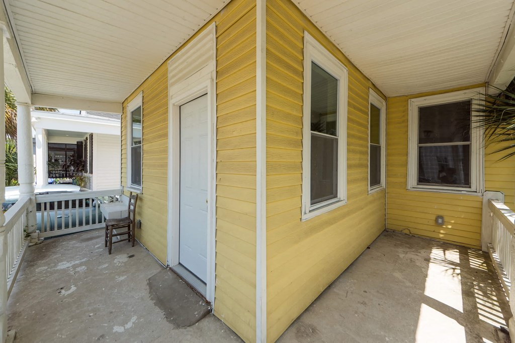 a yellow house with a white door and a porch