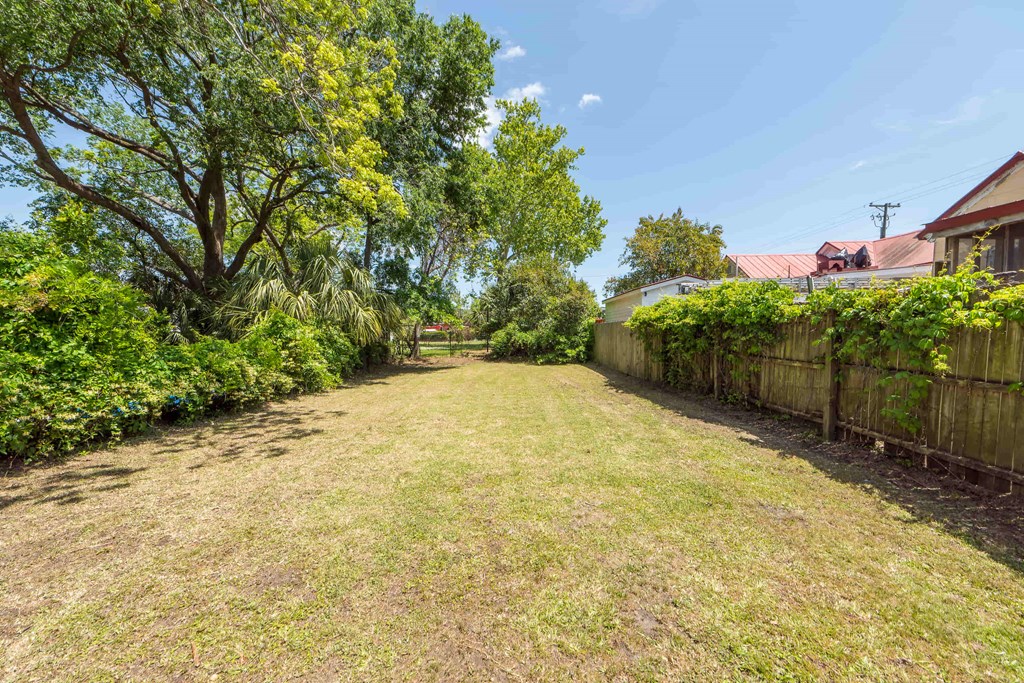 a yard with a fence and a house on the other side of it