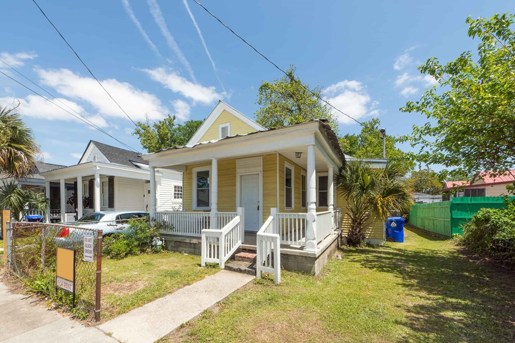 a small yellow house with a porch and a white