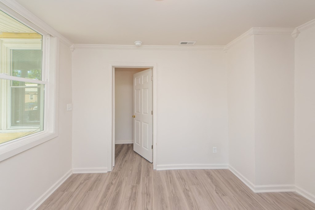 an empty room with white walls and wooden floors and a white door