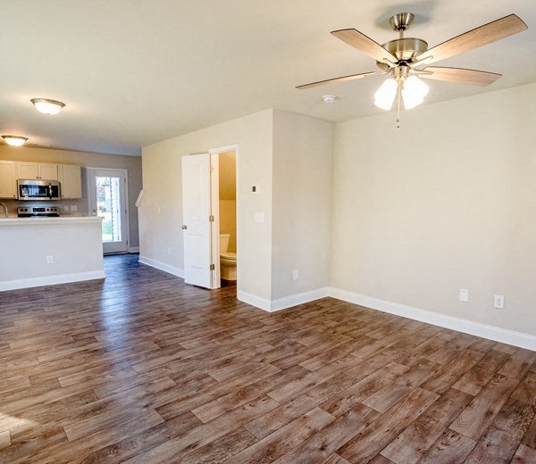 an empty living room and kitchen with a ceiling fan