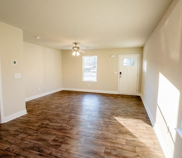 an empty living room with wood floors and a ceiling fan