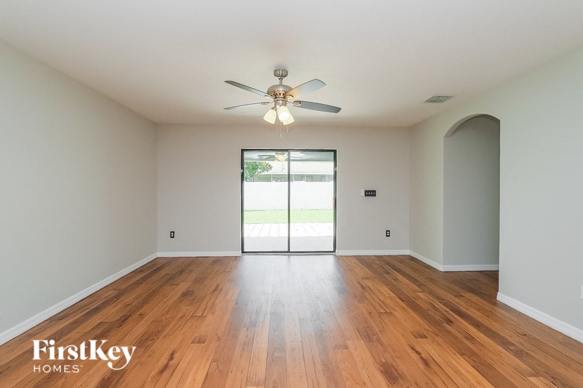 an empty living room with wood floors and a ceiling fan