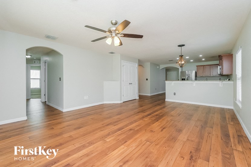 the living room and kitchen with hardwood flooring and a ceiling fan