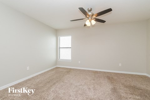 the spacious living room with ceiling fan and carpet