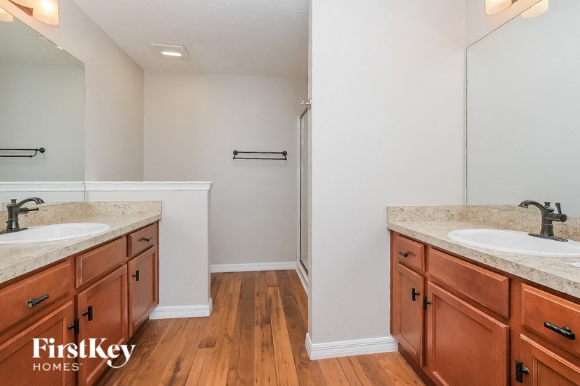 two sinks in a bathroom with wooden floors and a shower