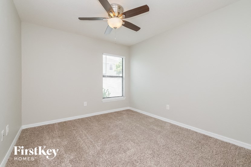 an empty room with a ceiling fan and a window