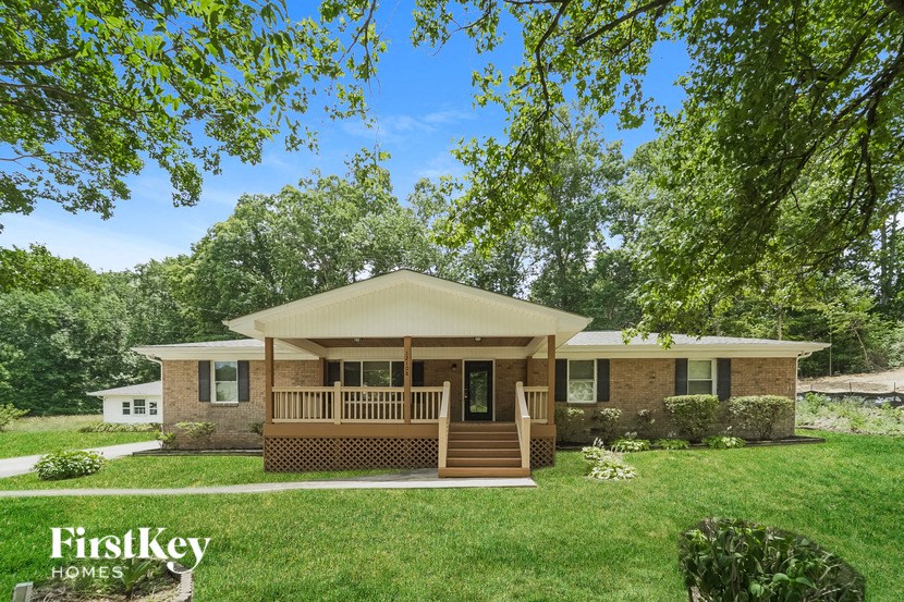 a small brick house with a covered porch and a lawn