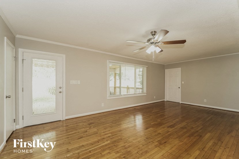 an empty living room with wood floors and a ceiling fan