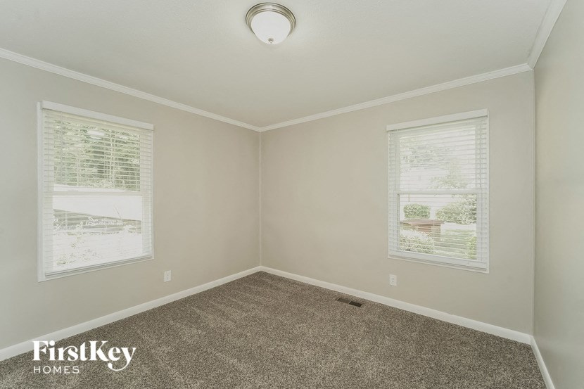 an empty room with a carpeted floor and two windows