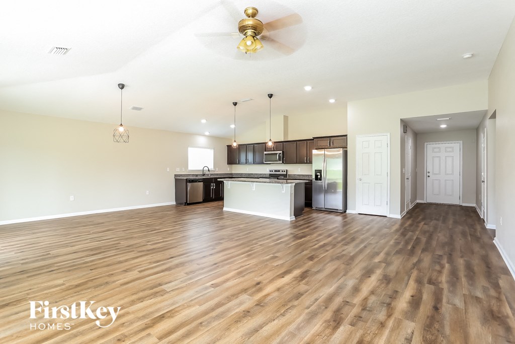 an open living room with a kitchen and a ceiling fan