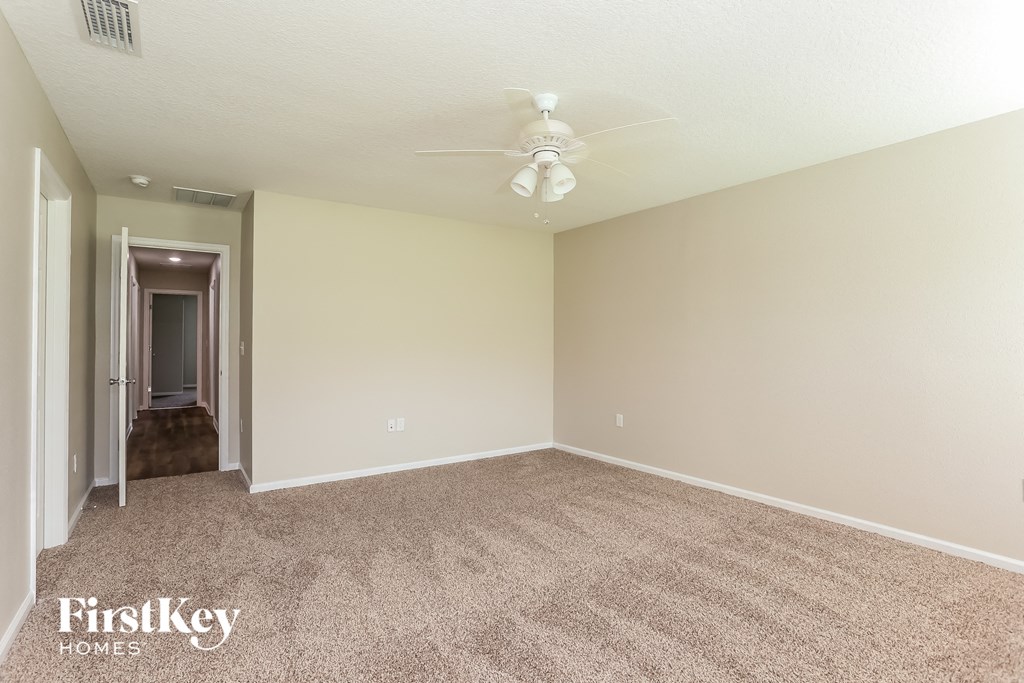 an empty living room with carpet and a ceiling fan