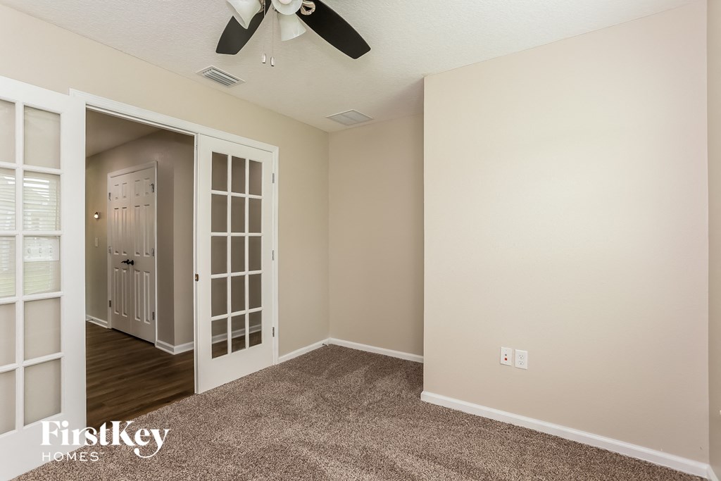 a bedroom with a ceiling fan and a door to a hallway