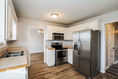 A kitchen with a stainless steel refrigerator and wooden floors.