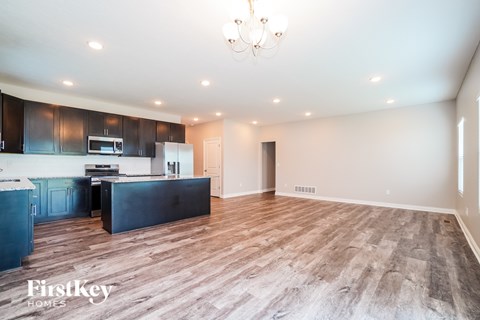 A spacious kitchen with dark wood cabinets and a light wood floor.
