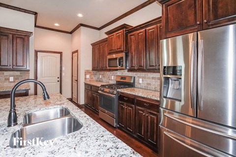 A kitchen with a stainless steel refrigerator and a granite countertop.