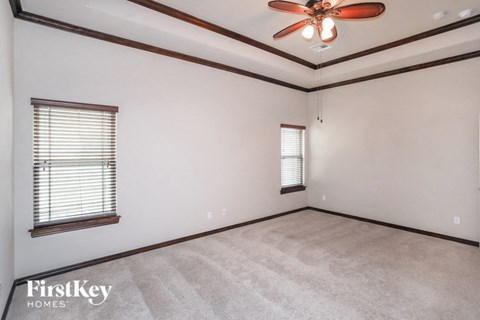 A room with a ceiling fan and two windows.