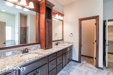A bathroom with a double sink vanity and a large mirror above it.