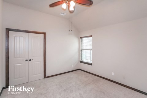 A room with a ceiling fan and a window with blinds.