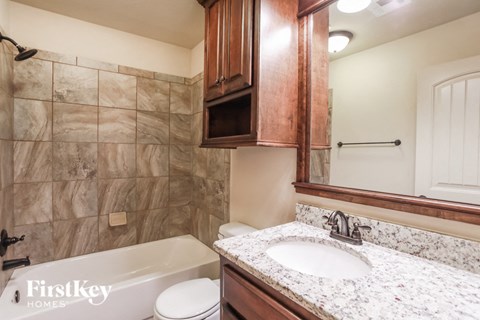 A bathroom with a marble counter top and wooden cabinets.