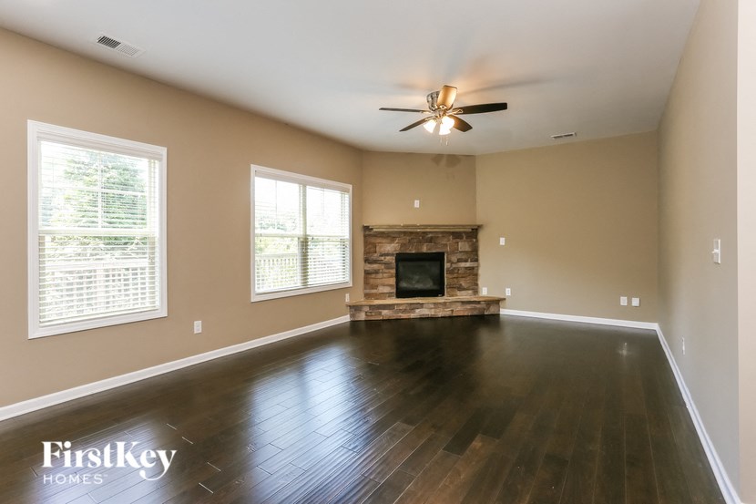 an empty living room with a fireplace and a ceiling fan