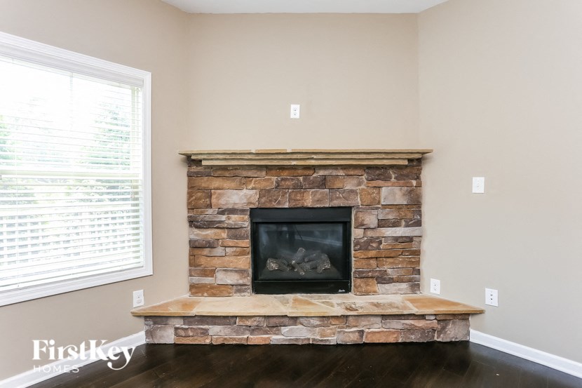 a stone fireplace in a living room with a wooden floor