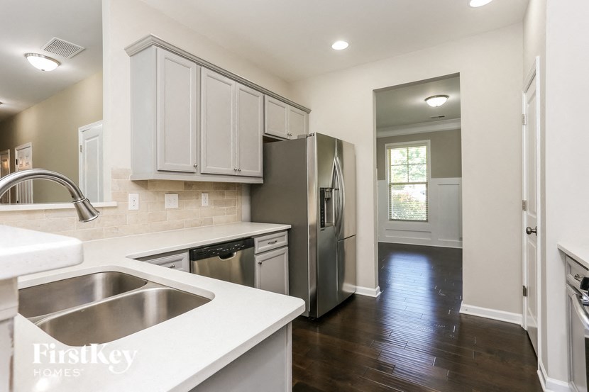 a kitchen with white cabinets and a stainless steel refrigerator and sink