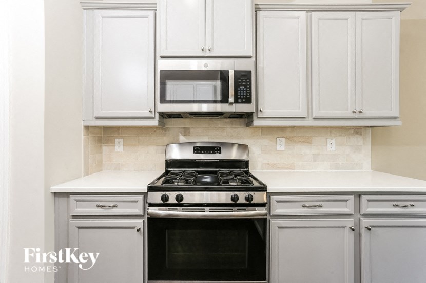 a white kitchen with white cabinets and a stove and microwave