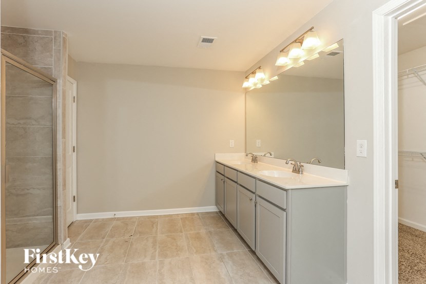the master bathroom has a large vanity and a walk in shower