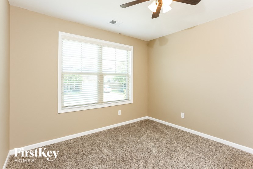 a bedroom with carpet and a window and a ceiling fan