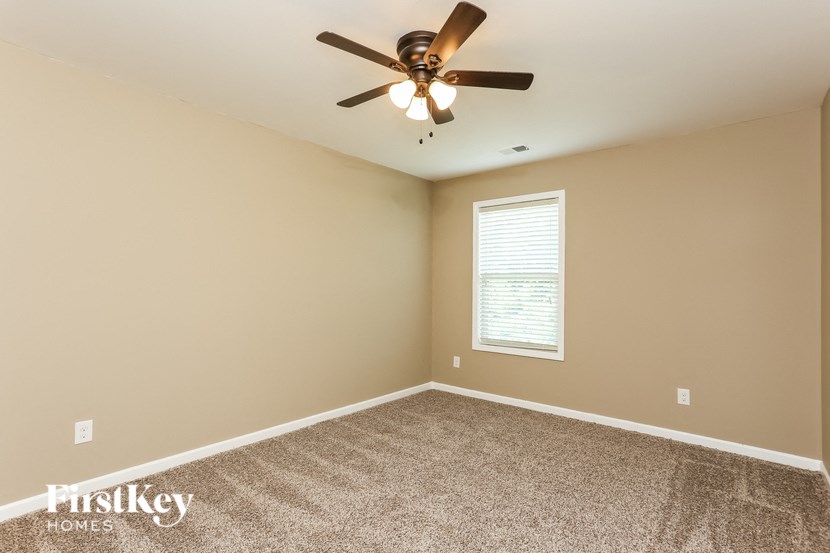 the master bedroom has a ceiling fan and a carpeted floor