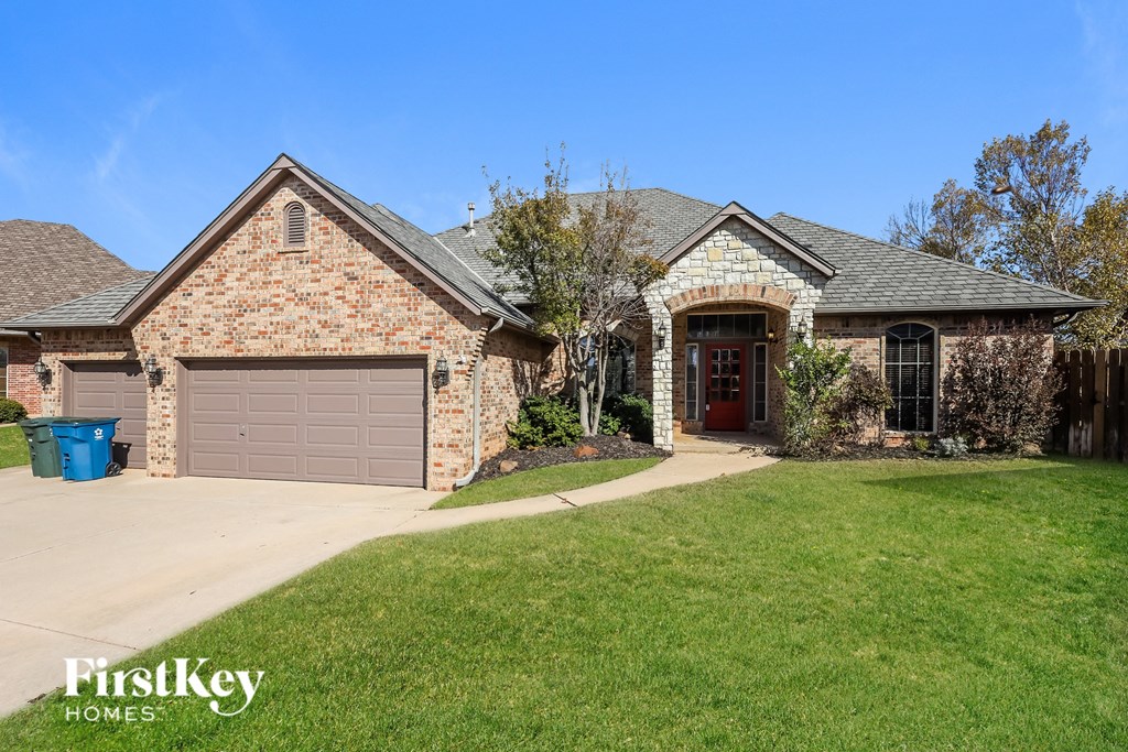 a brick house with a garage and a green lawn
