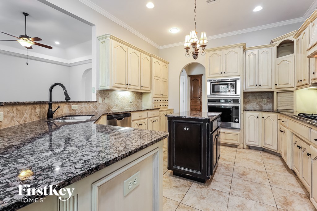 a kitchen with white cabinets and granite counter tops and black appliances