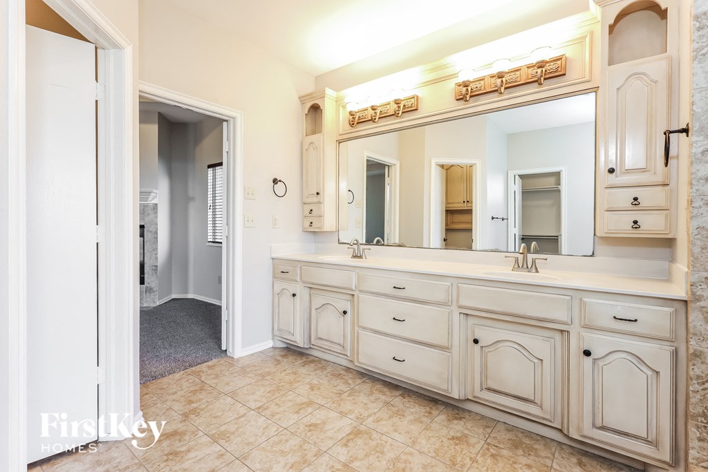a large bathroom with white cabinets and a large mirror