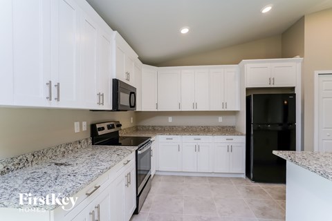 A kitchen with white cabinets and granite countertops.